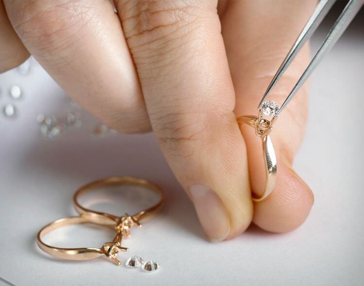 A person is working on a ring with tweezers