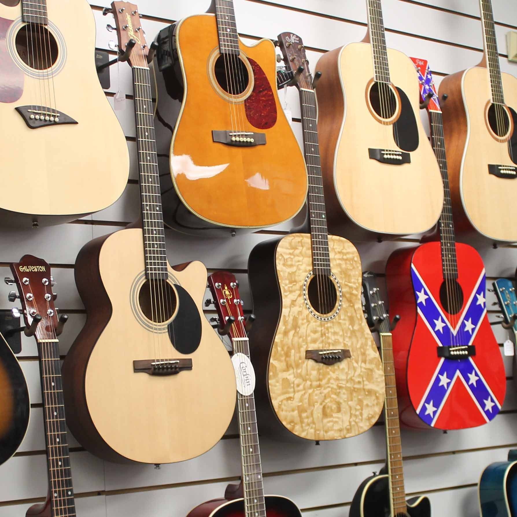 A bunch of acoustic guitars are hanging on a wall