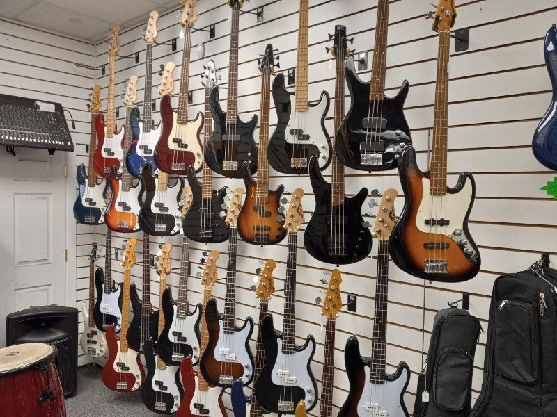 A bunch of guitars are hanging on a wall in a store
