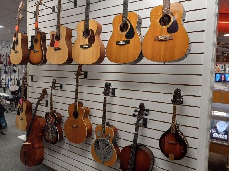 Many guitars are hanging on a wall in a store