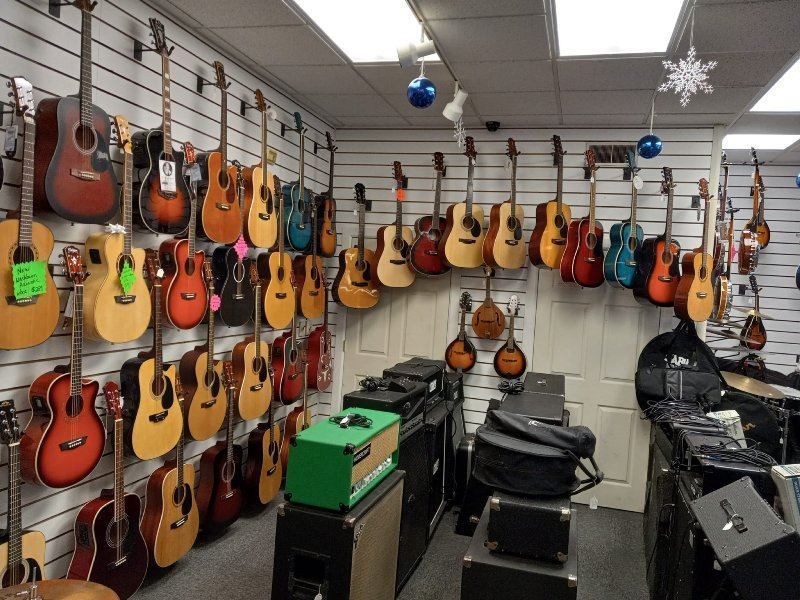 A guitar store with many guitars hanging on the wall