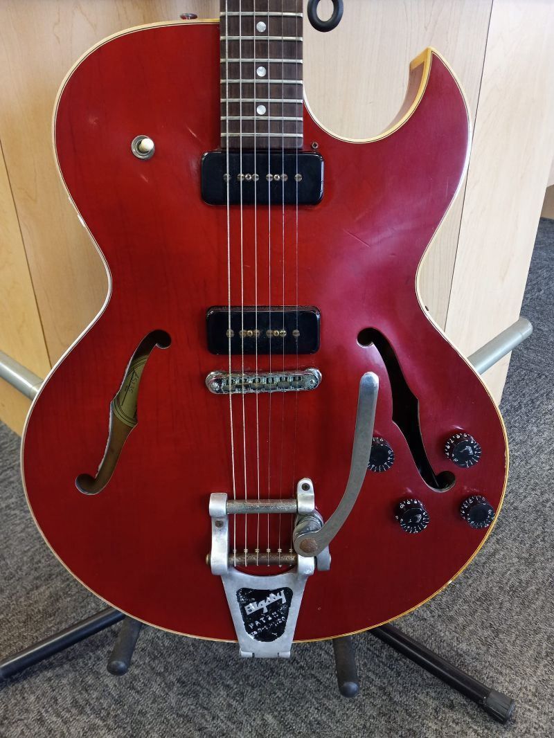 A red gibson guitar is sitting on a stand