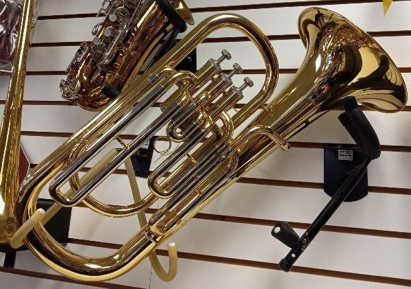 A trumpet is hanging on a wall next to a saxophone