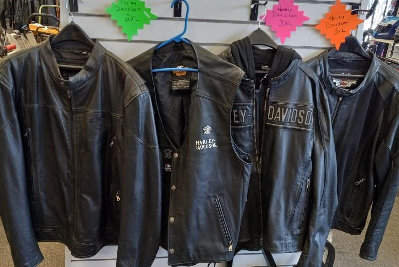 A bunch of harley davidson leather jackets are hanging on a rack