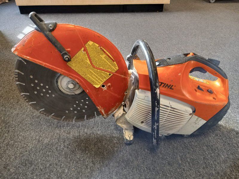 A stihl circular saw is sitting on a carpeted floor