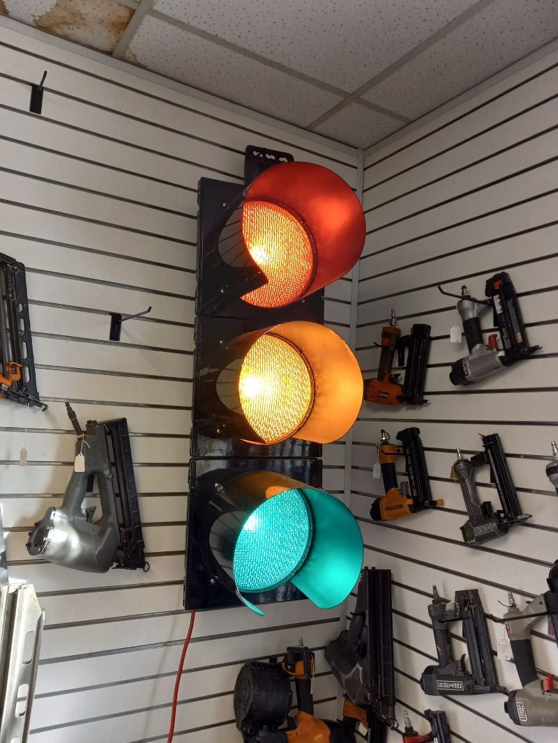 A traffic light is hanging on a wall in a room filled with tools.