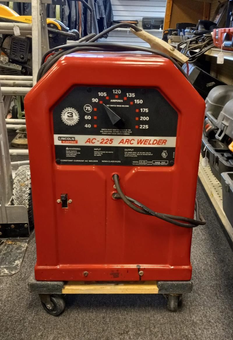 A red welding machine is sitting on a cart in a store.
