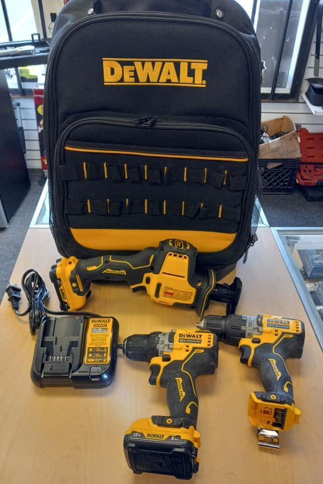 Three dewalt tools are sitting on a table next to a dewalt backpack.