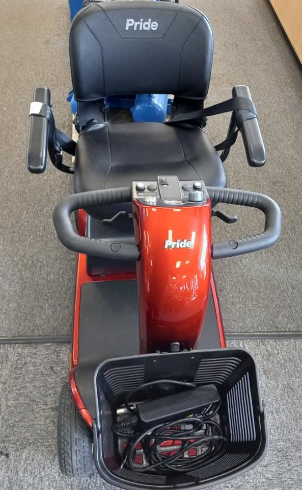 A red mobility scooter is sitting on the floor in a room.