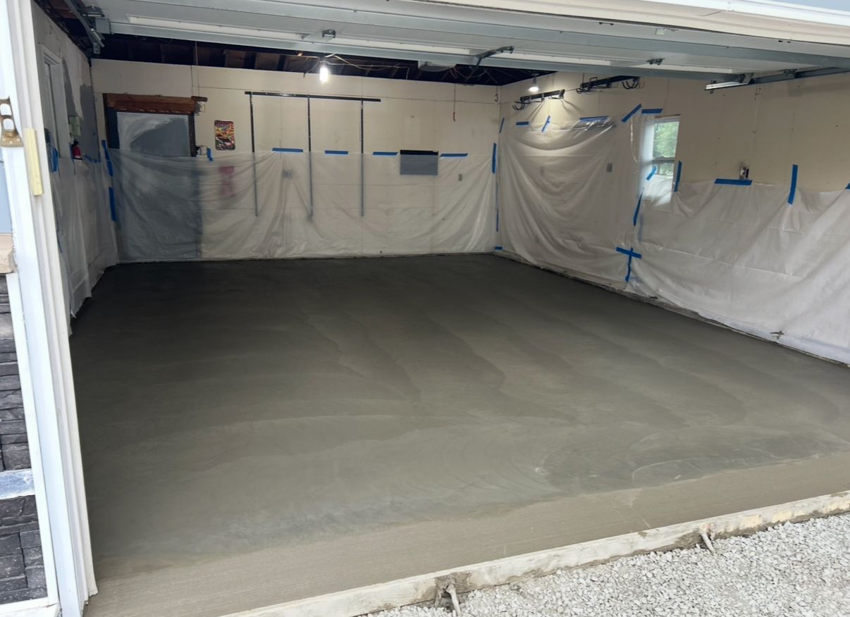 Newly poured concrete garage floor. Walls covered in plastic sheeting.