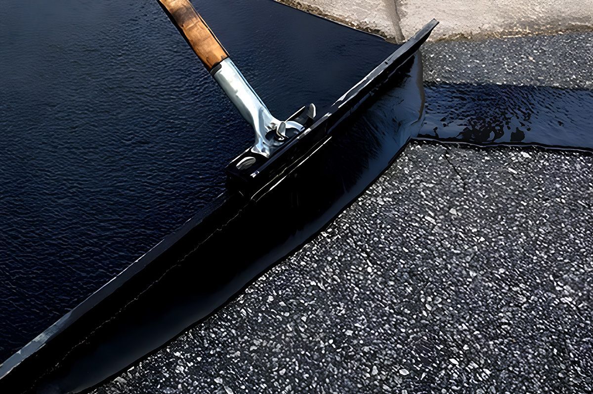 Black asphalt is being smoothed with a squeegee on a gray surface
