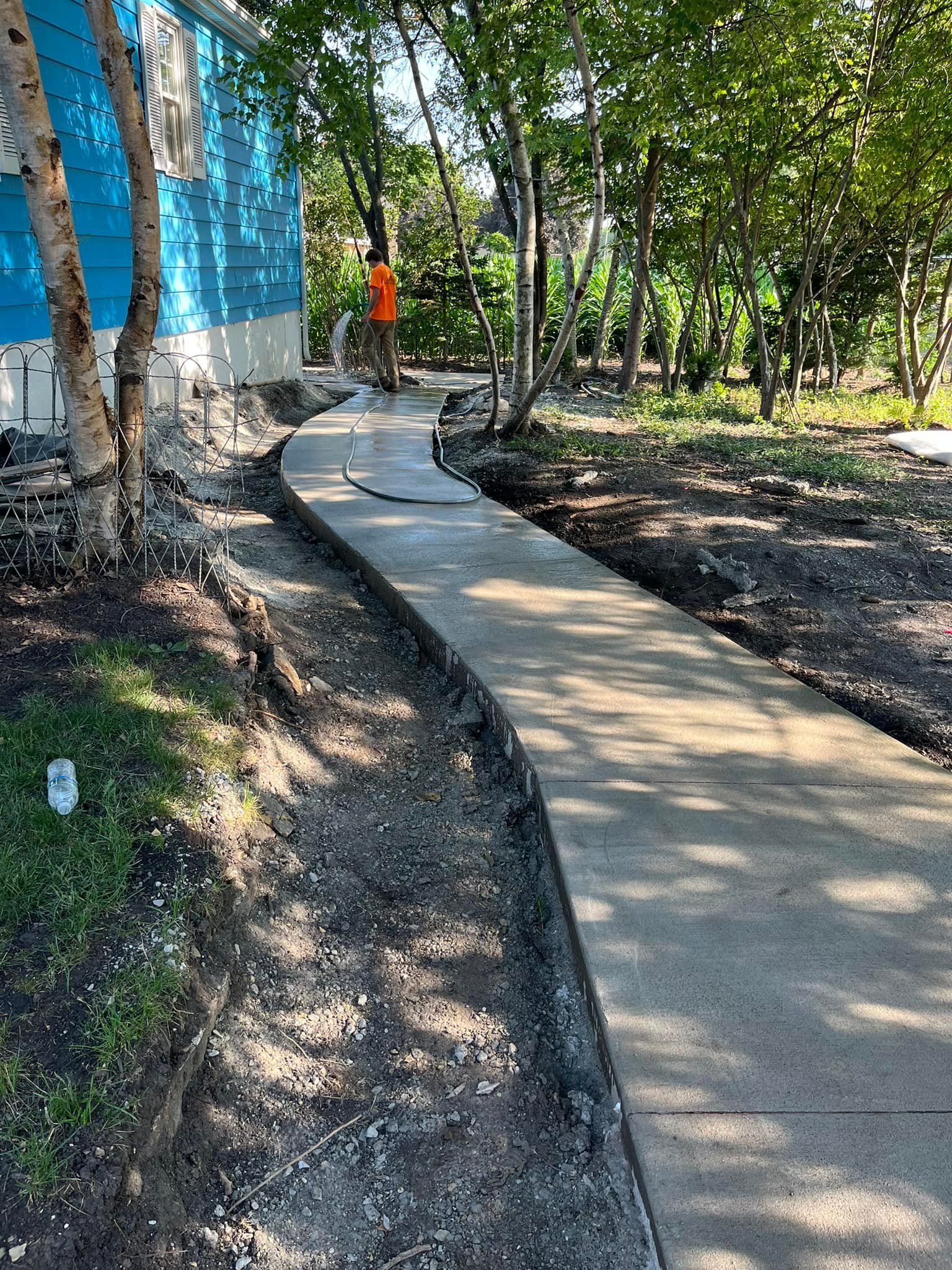 A concrete walkway is being built in front of a blue house.