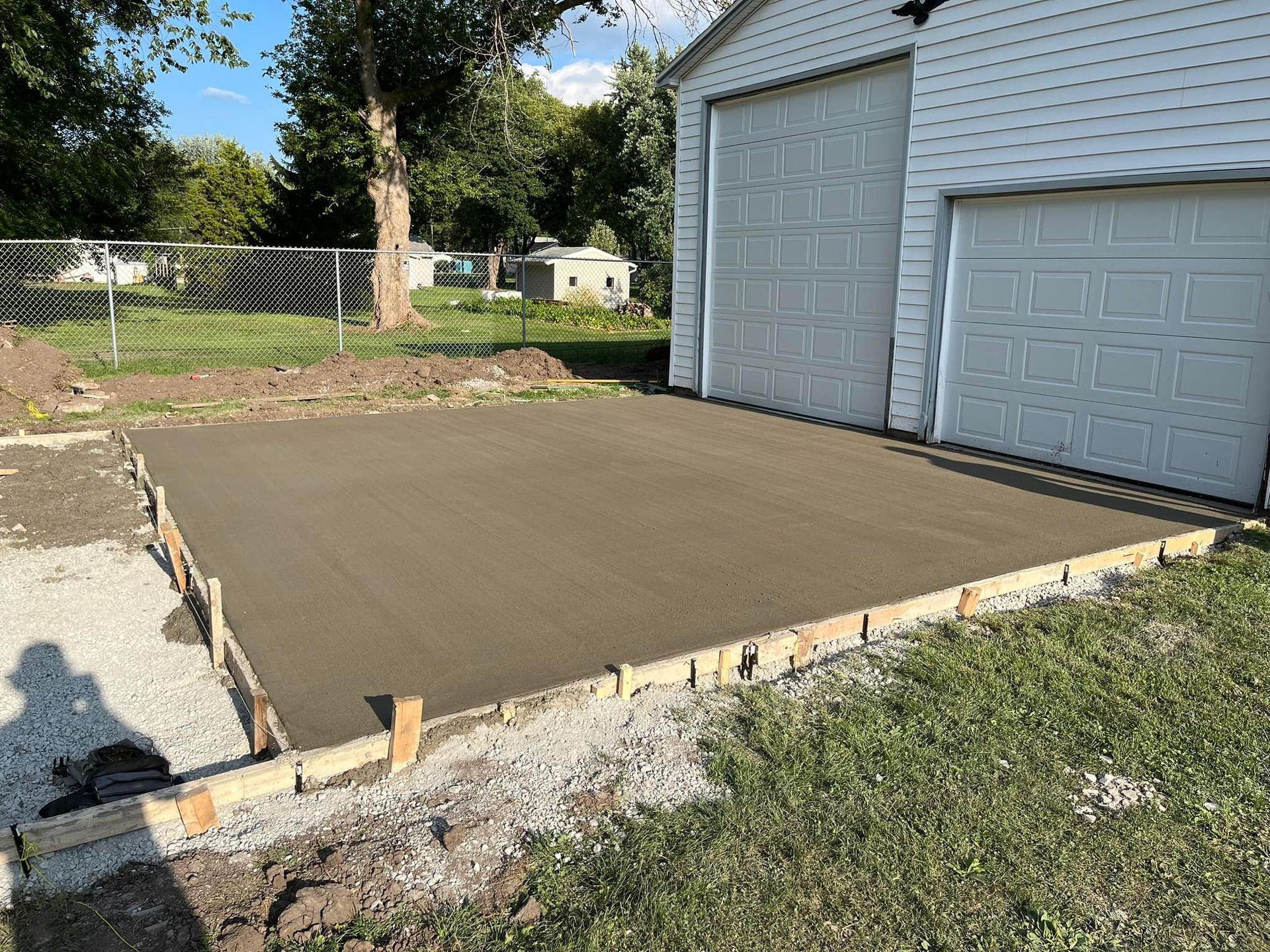A concrete driveway is being built in front of a garage.