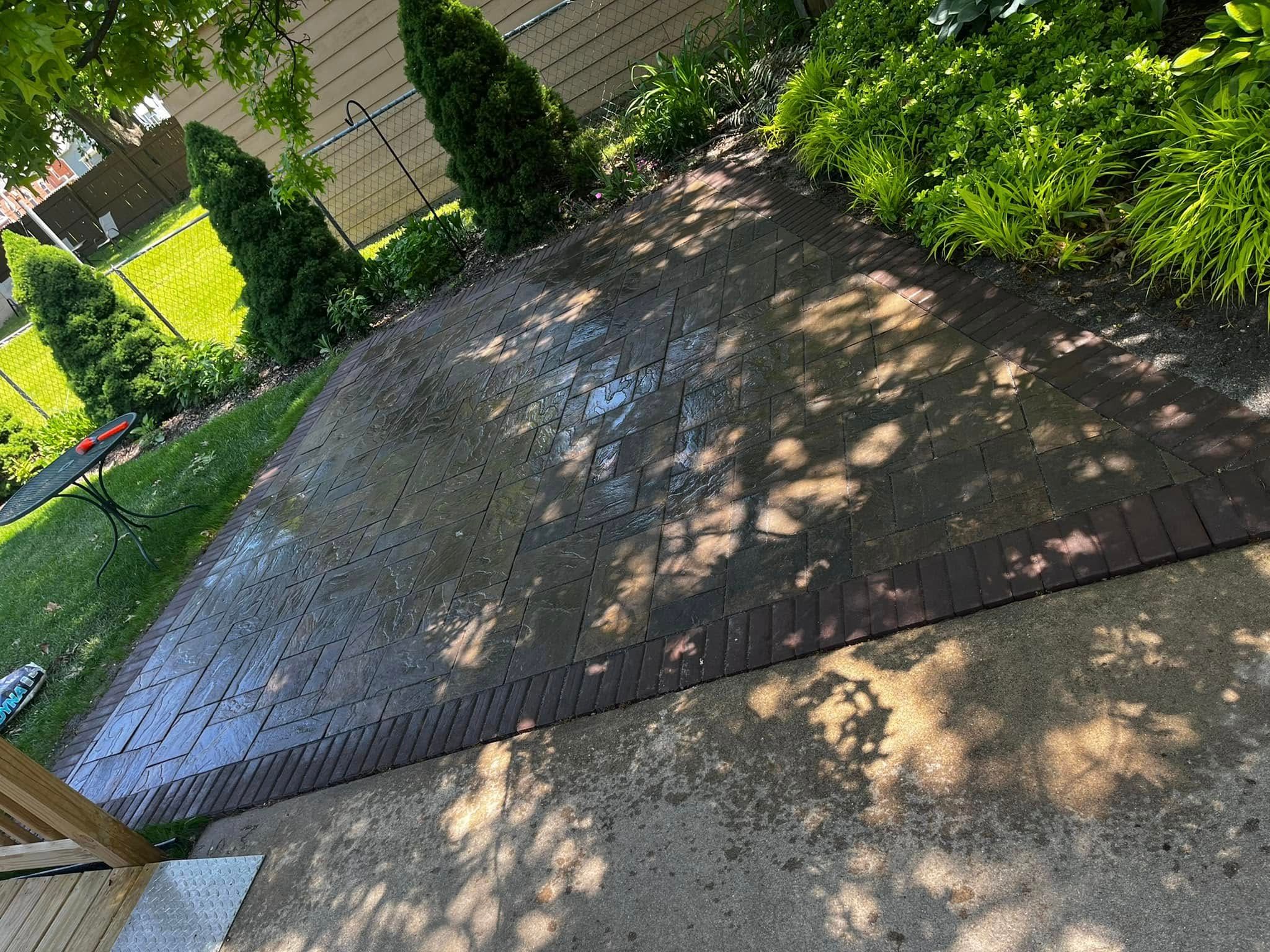 A patio with a brick walkway and a fence in the background.
