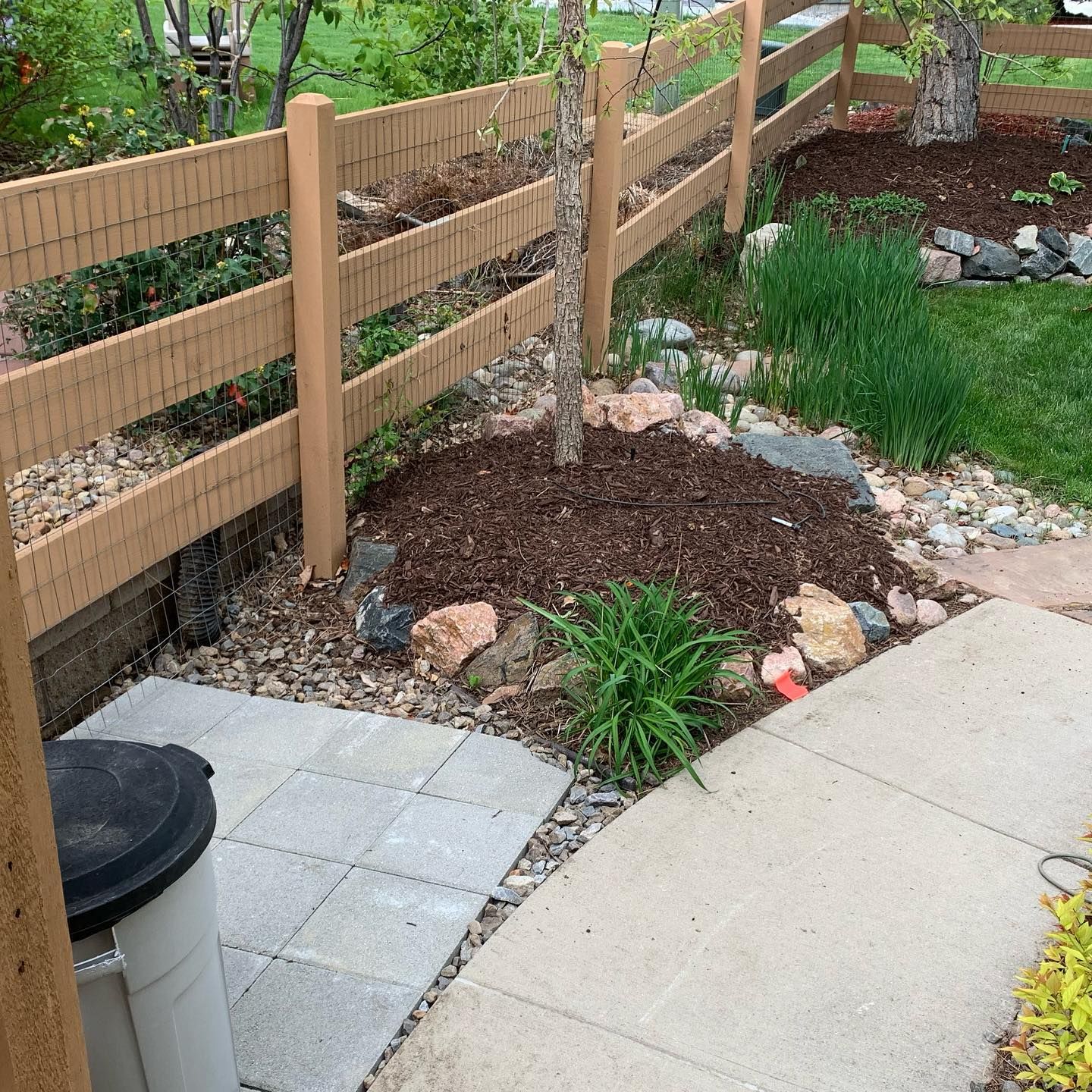 A wooden fence is surrounded by rocks and plants