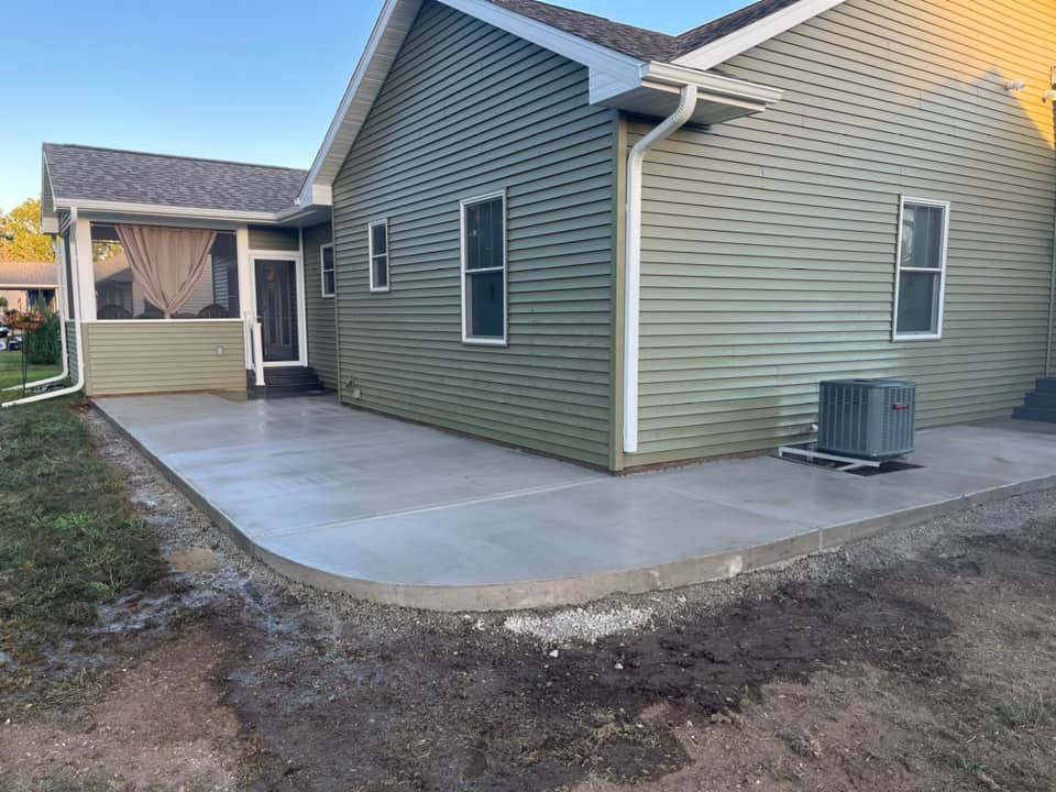 A green house with a concrete patio in front of it.
