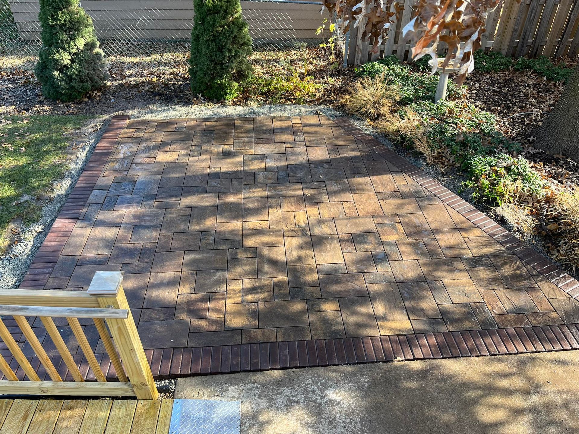 A brick patio with a wooden bench in the middle of it.