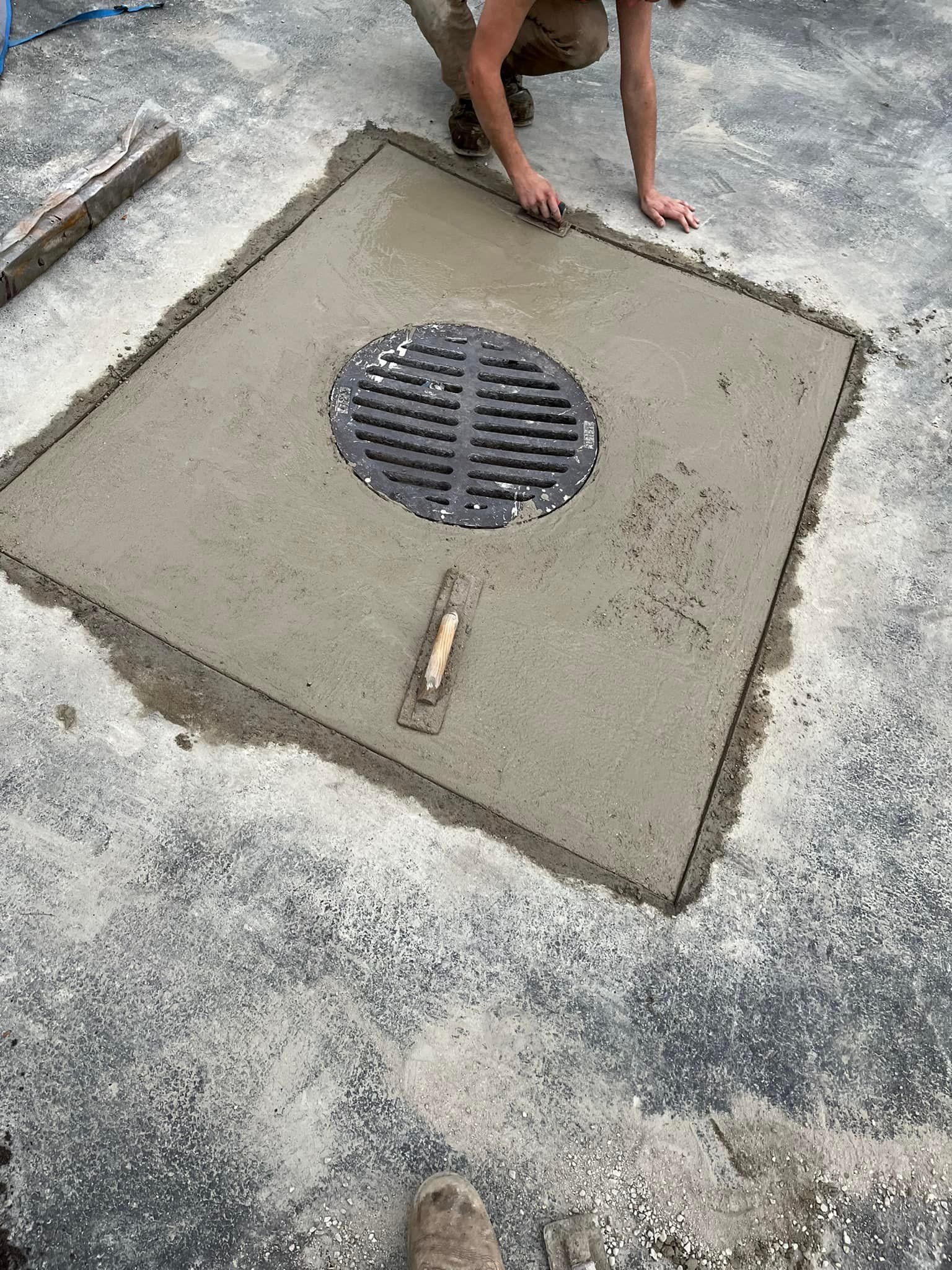 A manhole cover is being installed on the ground.