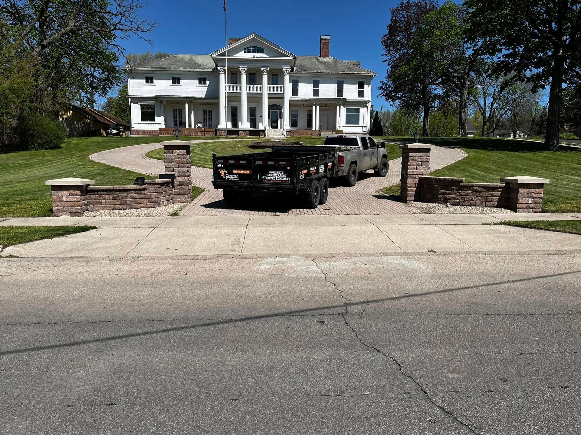 Two trucks are parked in front of a large white house.