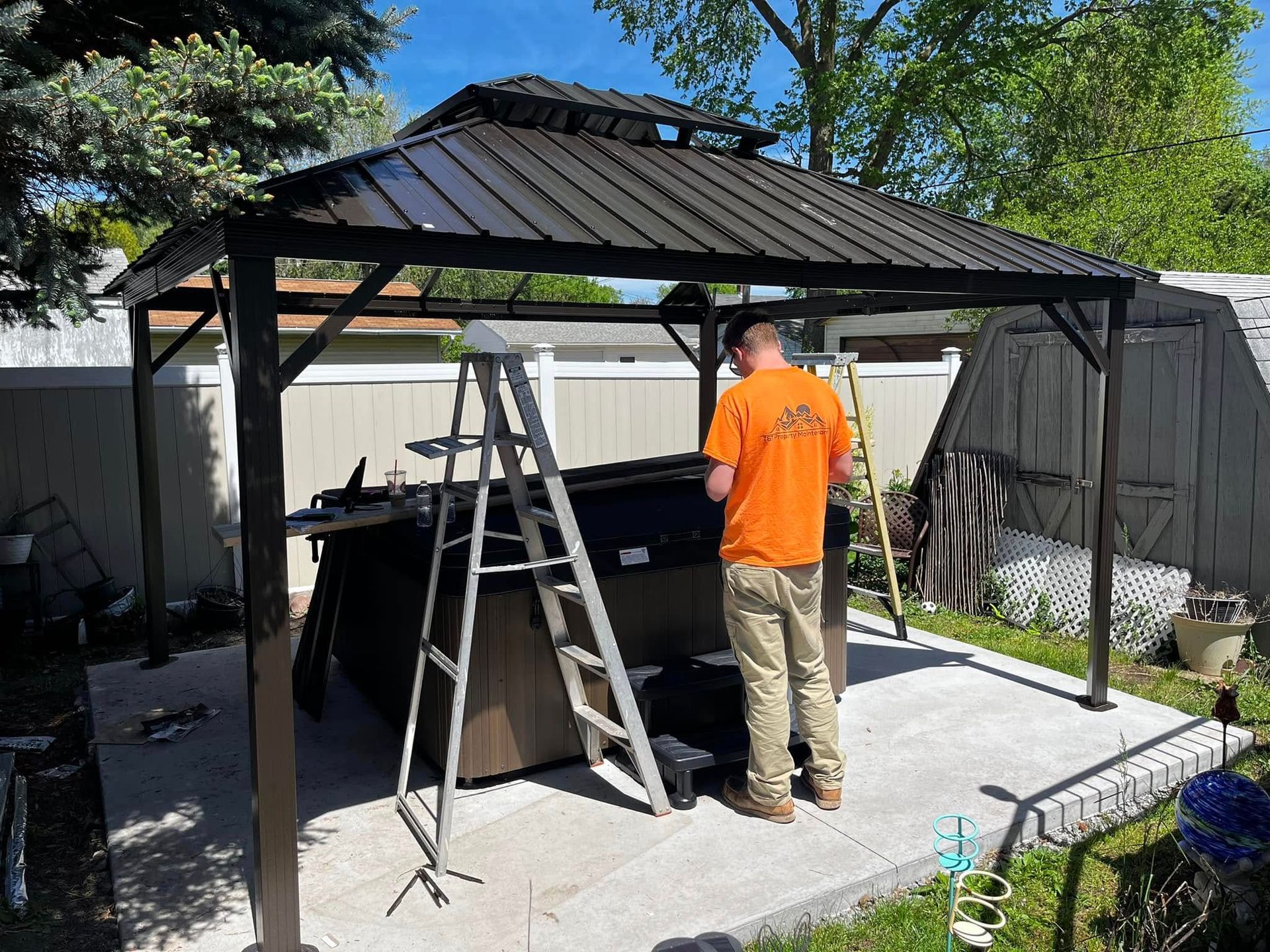 A man is standing under a gazebo in a backyard.