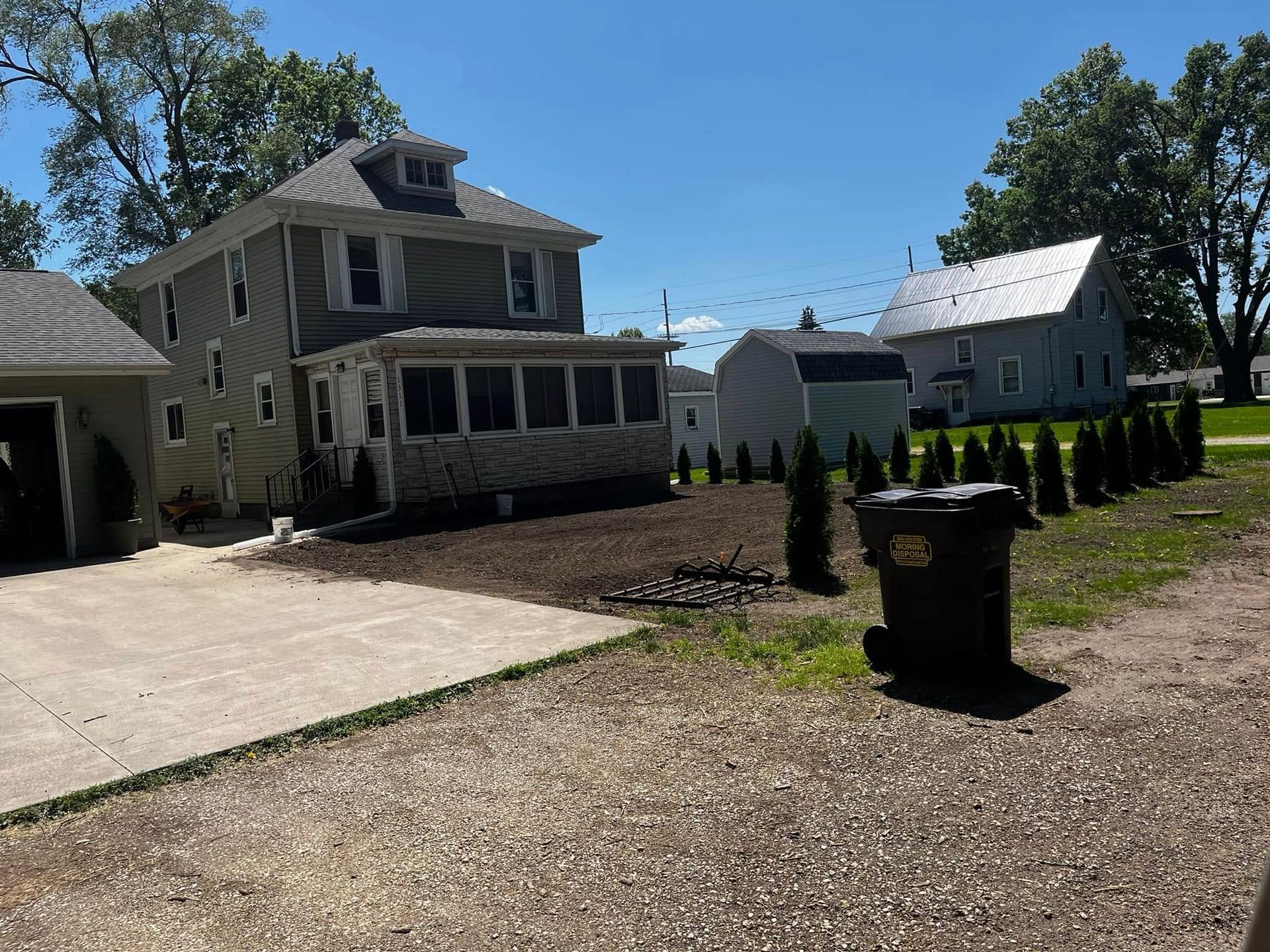 A house with a large driveway and a trash can in front of it