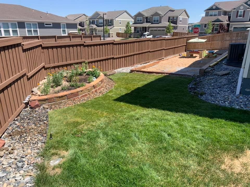 A backyard with a wooden fence and a lush green lawn.