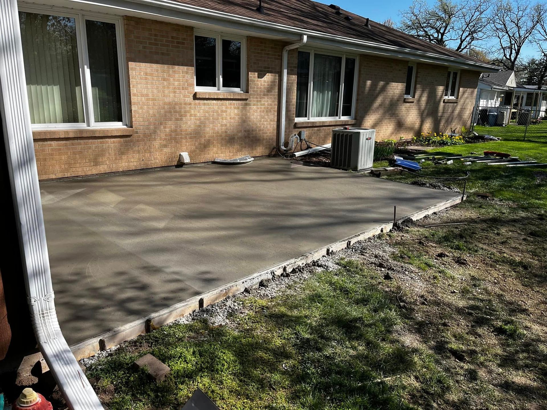 A brick house with a concrete patio in front of it.