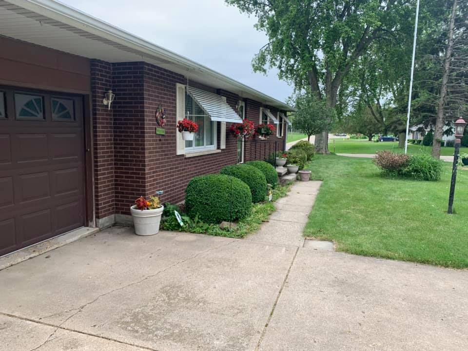 A brick house with a brown garage door and a walkway leading to it.