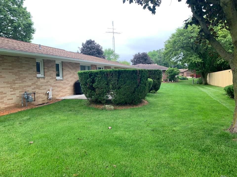 A brick house with a large lush green lawn in front of it.