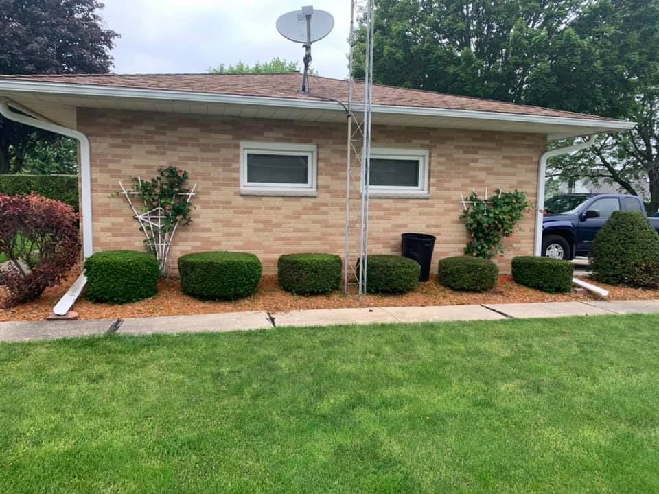 A brick house with a lot of bushes in front of it.