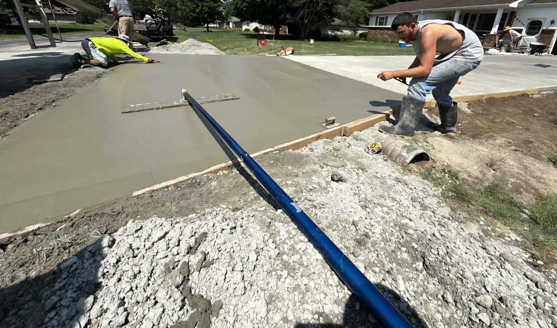 A group of construction workers are working on a concrete driveway.