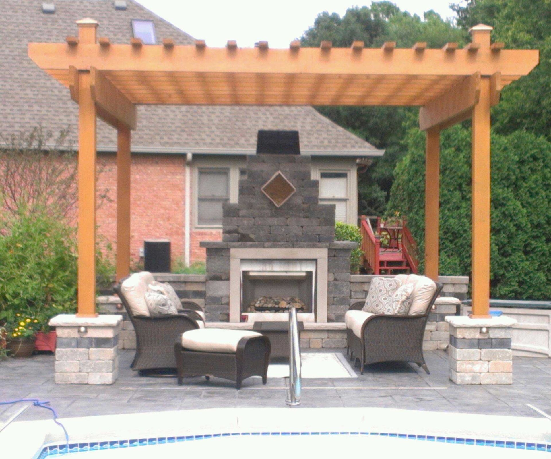 Wooden pergola over outdoor fireplace and seating area next to a pool.