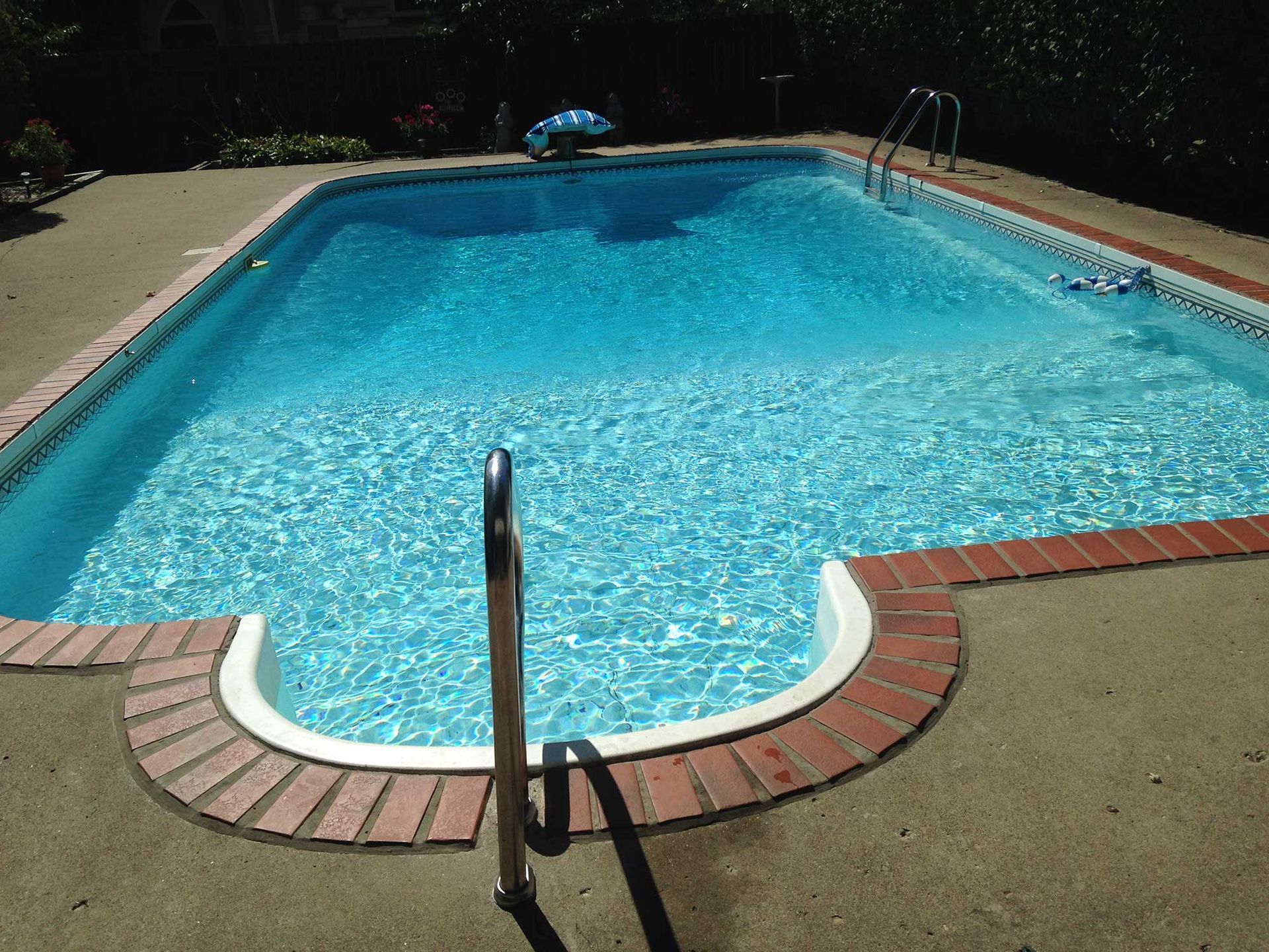 A rectangular swimming pool with clear blue water and brick coping.