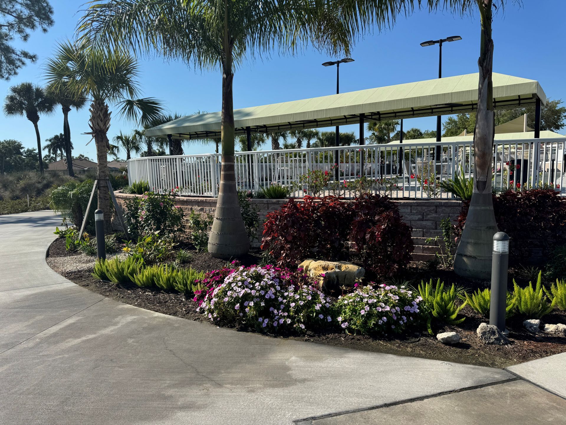 Landscaped garden with flowers and palm trees beside a pavilion on a sunny day
