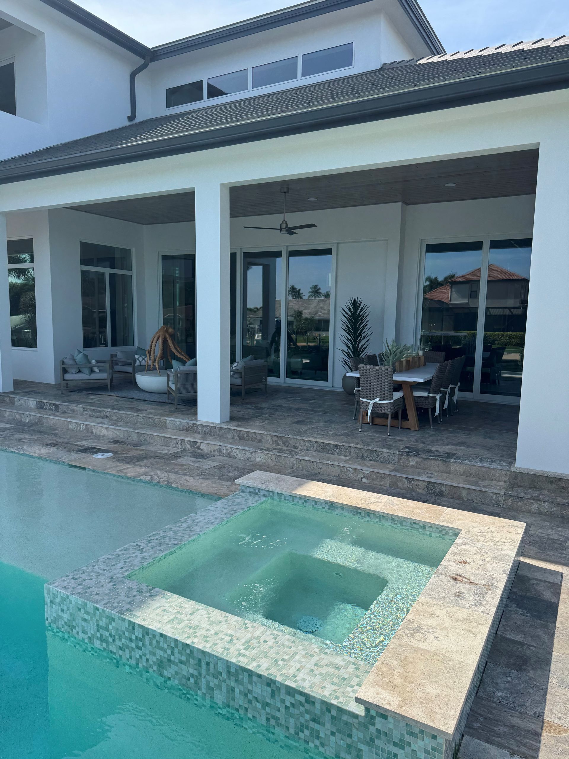 Modern house patio with a small tiled hot tub beside a swimming pool