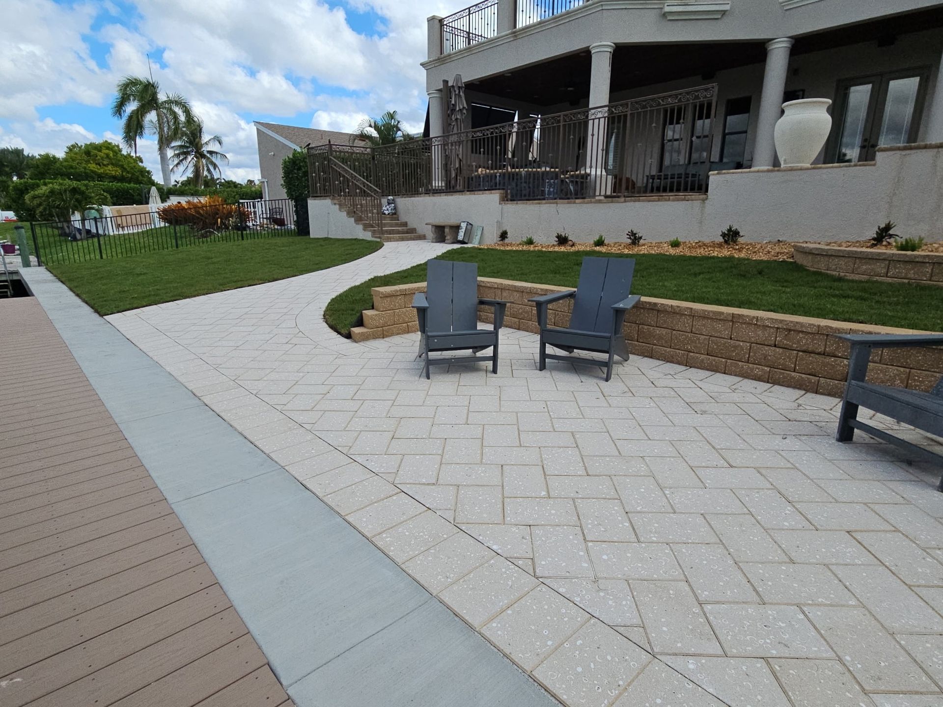 Outdoor patio with lounge chairs, paver walkway, grass, and a modern building under construction