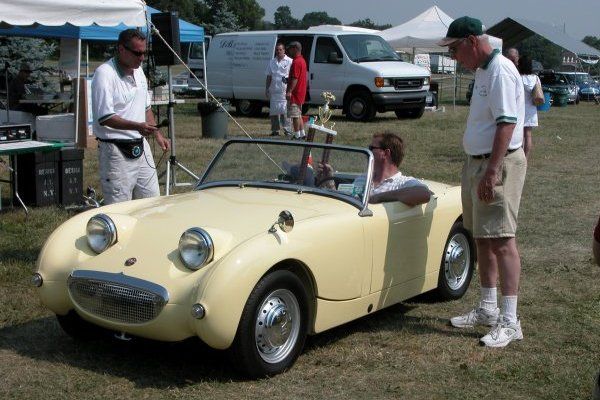 Man in a yellow car holding a trophy