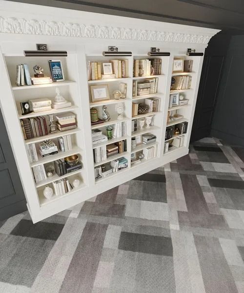 White built-in bookshelf filled with books and decor in a room with a patterned rug.