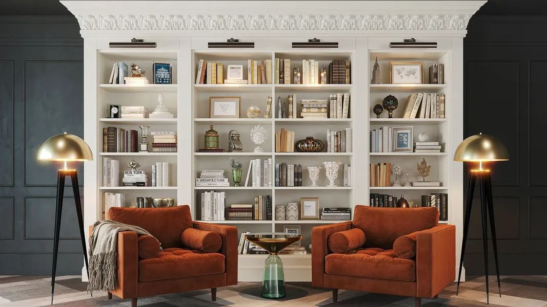 Cozy library with white bookshelves, orange armchairs, gold lamps, and books; dark blue wall.