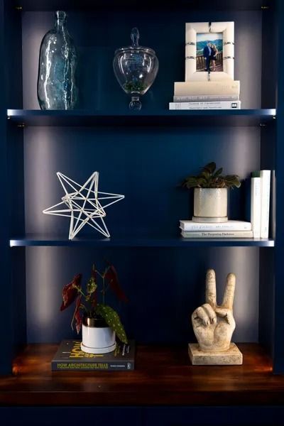 Blue shelves with decorative objects: glass bottles, star sculpture, books, peace sign.