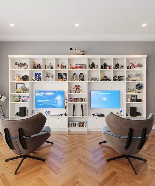 Gaming room with built-in white shelves displaying collectibles, flanked by armchairs facing TVs with blue screens.