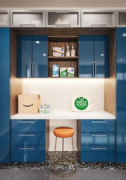 Blue cabinets and desk in a home office with products and an orange stool.