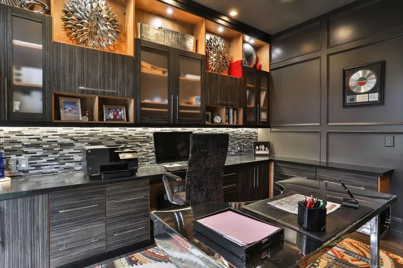 Dark wood home office with desk, built-in cabinets, shelves, and a patterned rug.