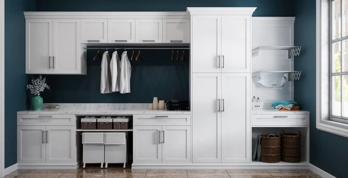 White laundry room cabinets, hanging rod, baskets, and blue wall.
