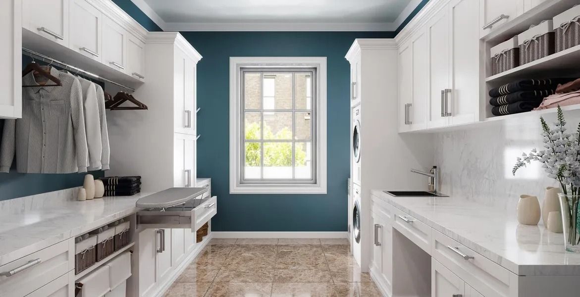 Laundry room with white cabinets, blue walls, and a window.