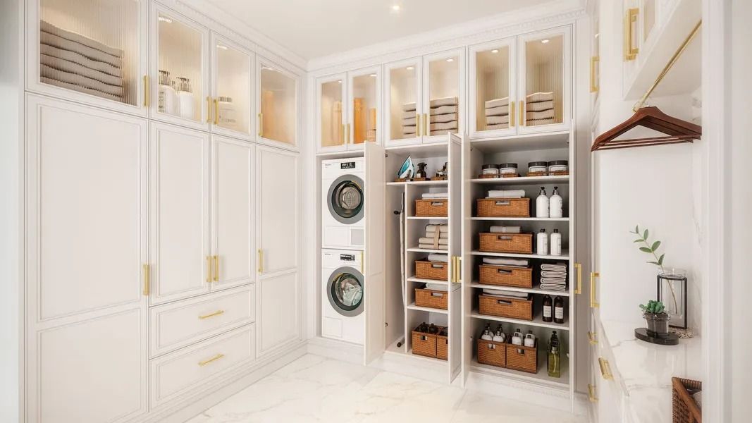 White laundry room with stacked washer/dryer, cabinets, shelves, and gold accents.