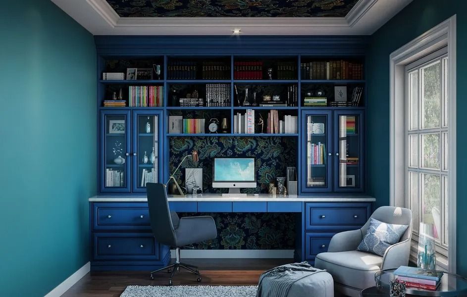 Blue home office with built-in desk, bookshelves, and a window; teal walls and floral accent wallpaper.