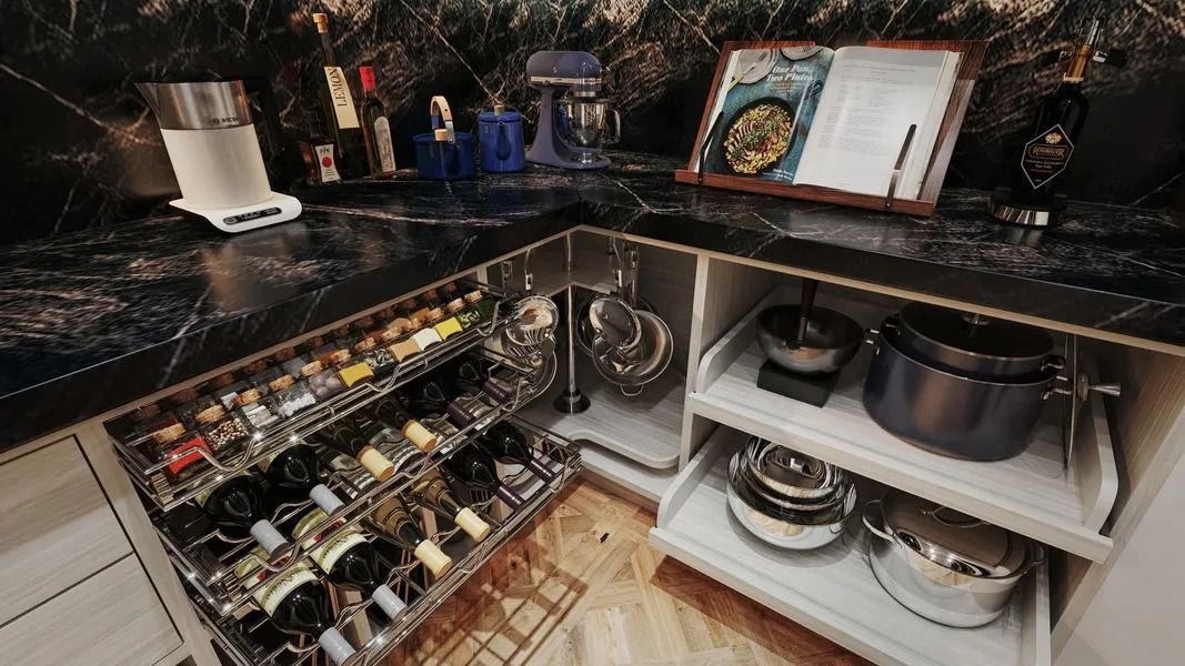 Kitchen corner: pull-out spice rack and pot storage below a dark marbled countertop; cookbooks and mixer on the counter.