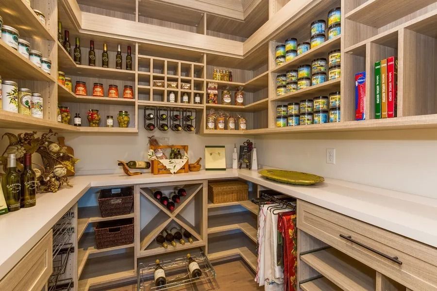 Walk-in pantry with light wood shelving, various food items, and wine storage.