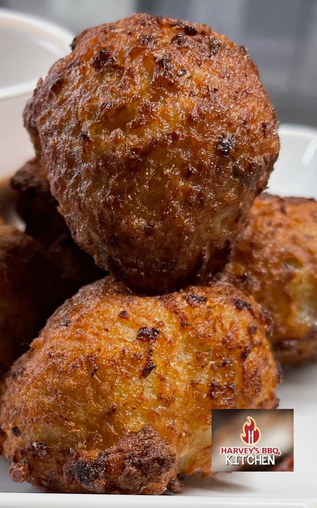Close-up of golden-brown, deep-fried fritters stacked on a plate.